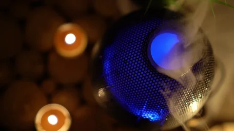Close up of aroma electric oil diffuser lamp, candles on wooden table in room. Stock Footage 129297138