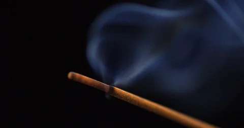 Close up of aromatic incense stick smokes against a black background Stock Footage 128844679