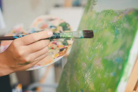 Close-up art student's hand using watercolor paint brush painting on canvas.. Stock Photos