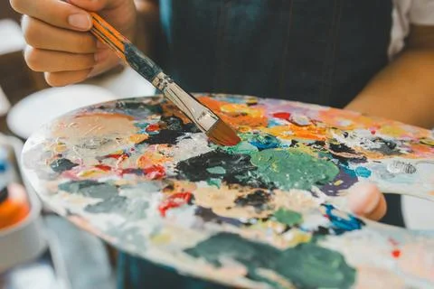 Close-up Art student's hand using a paintbrush to mix colors on a palette i.. Stock Photos