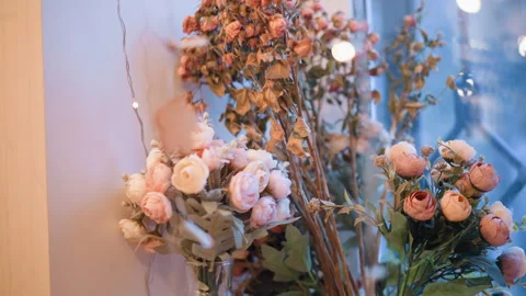 Close up artificial pink and peach rose bouquets with green foliage in soft lit Stock Footage 346729905