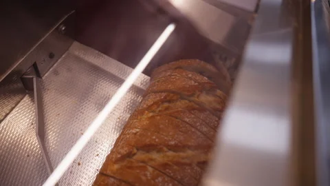 Close up of artisan bread loaf moving on conveyor belt and being sliced by .. Stock Footage 331799876