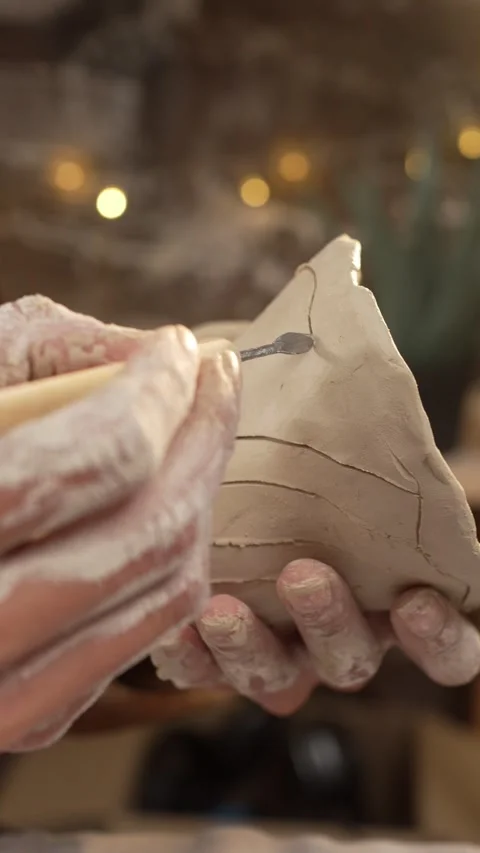 Close-up of an artisan carving fine lines and elegant patterns on a clay mu.. Stock Footage 335881656