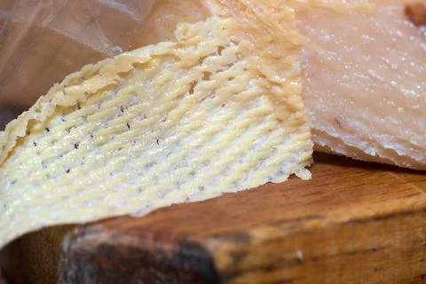 Close-up of artisan cheese slice with textured surface on wooden board Stock Photos