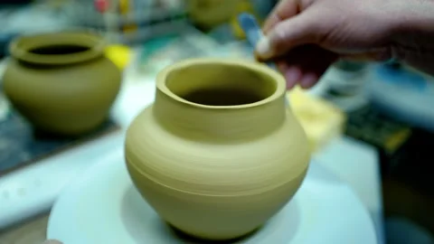 Close-up of an artisan using a pottery tool to smooth a raw clay vessel. Stock Footage 328925293