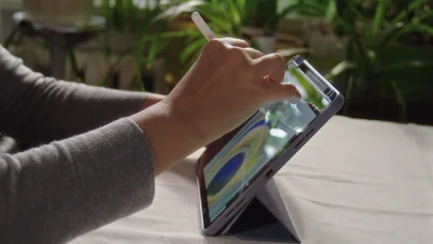 Close-up, artist drawing peacock feather on tablet screen while sitting at Stock-Footage 337122132
