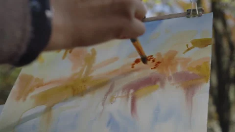 Close-up, the artist in front of the easel paints a landscape of an autumn Video stock 337120554