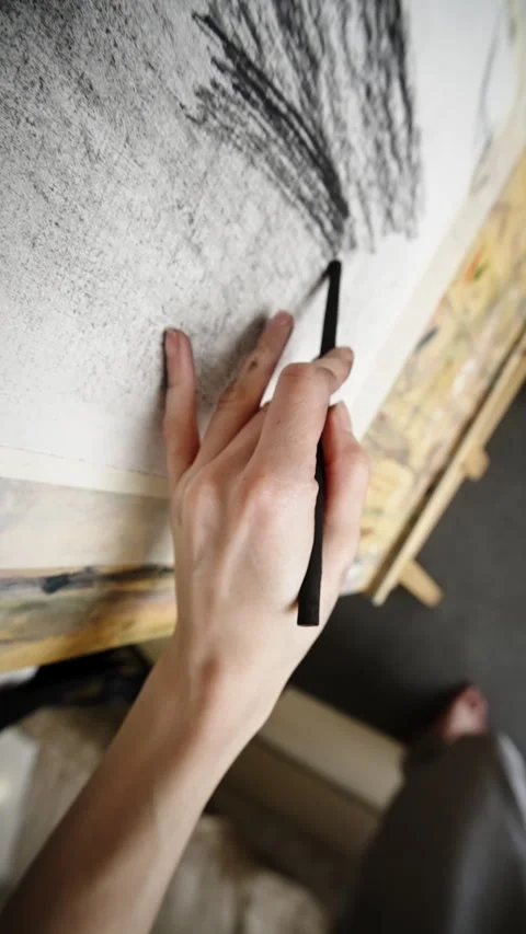 Close-up of an artist s hand using charcoal to sketch textured lines on large Видео 333126930