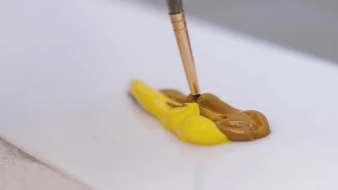 Close-up of artist using a brush to mix paint colors brown and yellow Stock Footage 140038001