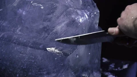Close up of artist using a knife to carve the ice to make a sculpture, 4k Stock Footage 153587616