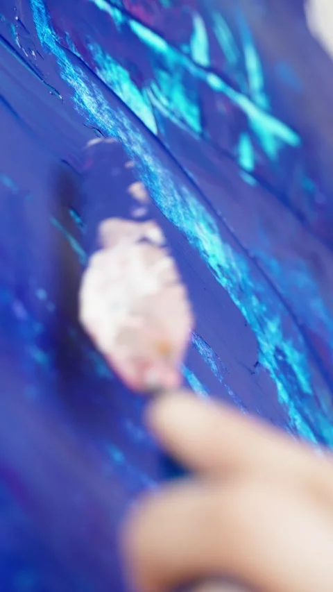 Close-up of an artist using a palette knife to spread vibrant blue acrylic Stock Footage 333127034