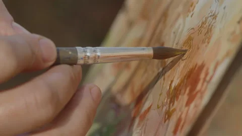 Close-up, the artist's hand with a brush paints an autumn landscape of the Video stock 337121448