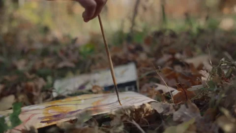Close-up, the artist's hand paints a forest landscape on the ground among Video stock 337119674