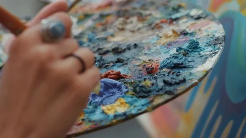 A close-up of the artist's hands holds a brush and a palette. Draw in paints. In Stock Footage