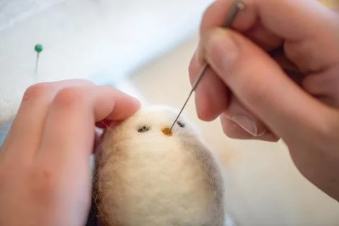 Close-up of artist's hands using a special needle to create a needle felted a Stock Photos