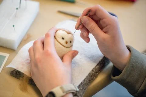 Close-up of artist's hands using a special needle to create a needle felted a Stock Photos
