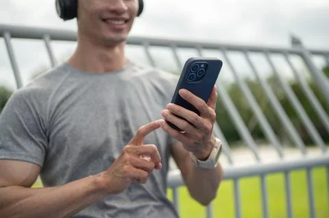 Close up of an asian athletic man using smartphone while listening to music.. Stock Photos