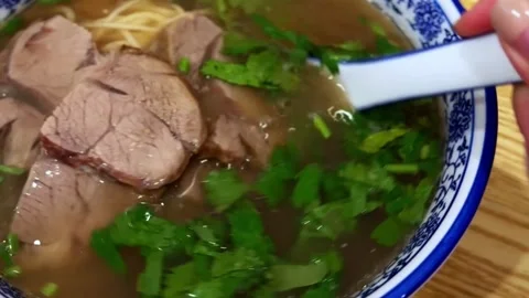 Close-up of Asian beef noodle soup in aromatic broth with fresh herbs. Stock Footage 325252574