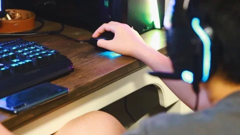 Close up of Asian boy playing game on his gaming computer with RGB gaming gear Stock Footage 107907616