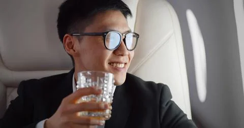 Close up of asian businessman drinking whiskey in glass in plane Stock Photos