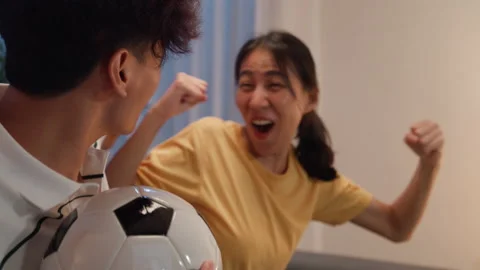 Close-up Asian couple sit on sofa excited cheering watching football sport game. Stock Footage 237618600