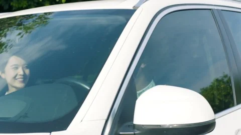 Close up of Asian couple smiling &amp; driving a car under trees Stock Footage 80357875