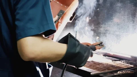 Close up of Asian factory worker perform electric welding causing sparks smoke Stock Footage 102571501