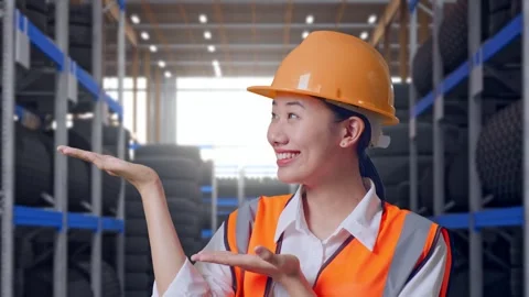 Close Up Of Asian Female Engineer Smiling And Pointing To Side at Tire Warehouse Stock Footage 341788478