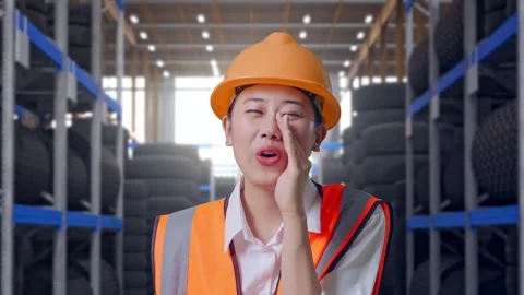Close Up Of Asian Female Engineer Yelling With Hand Over Mouth at Tire Warehouse Video stock 341788540