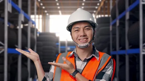 Close Up Of Asian Male Engineer Smiling And Pointing To Side at Tire Warehouse Stock Footage 341787017