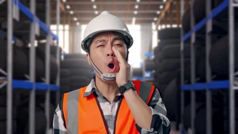 Close Up Of Asian Male Engineer Yelling With Hand Over Mouth at Tire Warehouse Video stock 341787161