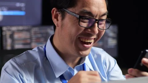 Close Up Of Asian Male Programmer Looking At Smartphone Celebrating The Success Stock Footage 230181790