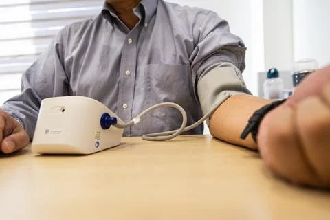 Close up of Asian man in 50s checking blood pressure with instrument in the work Stock Photos