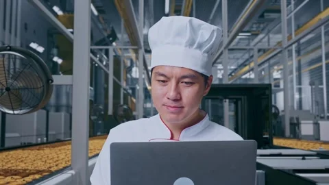 Close Up Of Asian Man Chef Using A Laptop And Pointing To Side In Cookie Factory Vidéo 318081637