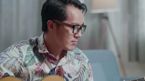 Close Up Of Asian Man Composer With Notebook On Table Playing Guitar At Home Stock Footage 200889923