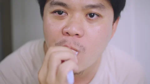 Close-up of Asian Man Looking at Mirror While Brushing Teeth,  Stock Footage 337769147