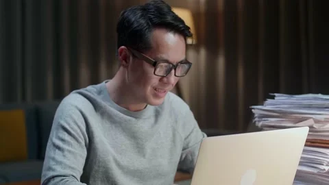 Close Up Of Asian Man Typing Laptop Computer While Working With Documents Stock Footage 196928068