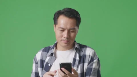 Close Up Of Asian Man Using Mobile Phone While Walking On Green Screen Stock Footage 248006446