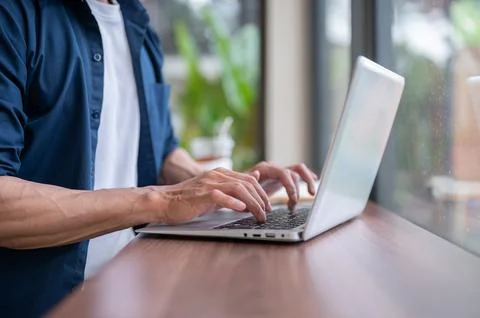 Close up of asian man's hands typing on laptop at wooden table while workin.. Stock Photos
