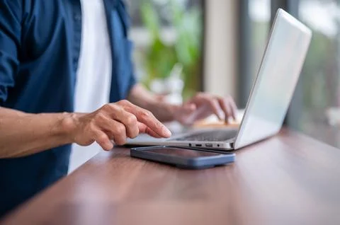 Close up of asian man's hands working on laptop and touching a smartphone o.. Stock Photos