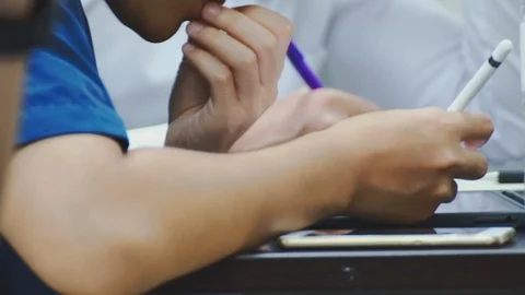 Close up of asian students taking notes during a class on their tablet pc Stock Footage 107613663
