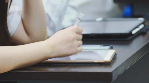 Close up of asian students taking notes during a class on their tablet pc Stock Footage 107614154