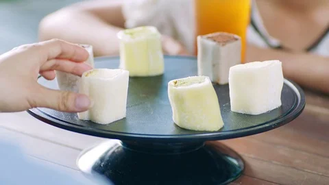Close up of an asian woman’s hand picking up a cake at outdoor seating Stock Footage 80299902