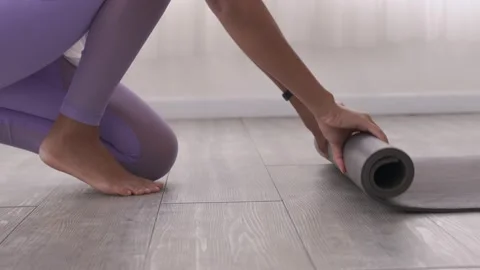 Close up Asian woman's hands rolling up her yoga mat after a workout at the s Stock Footage 164126859