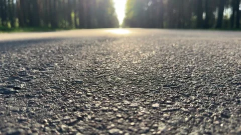 Close-up of asphalt road at sunset with blurred forest in the background Vídeo Stock 334068958