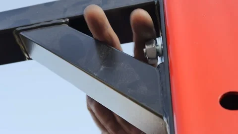 Close-up of the assembler's fingers tightening a nut onto a bolt thread in a Stock Footage 203592296