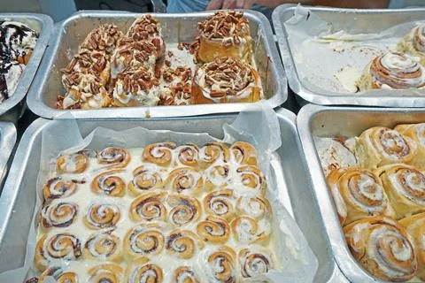 Close up assorted chocolate and nutty cinnamon rolls in aluminum trays Stock Photos