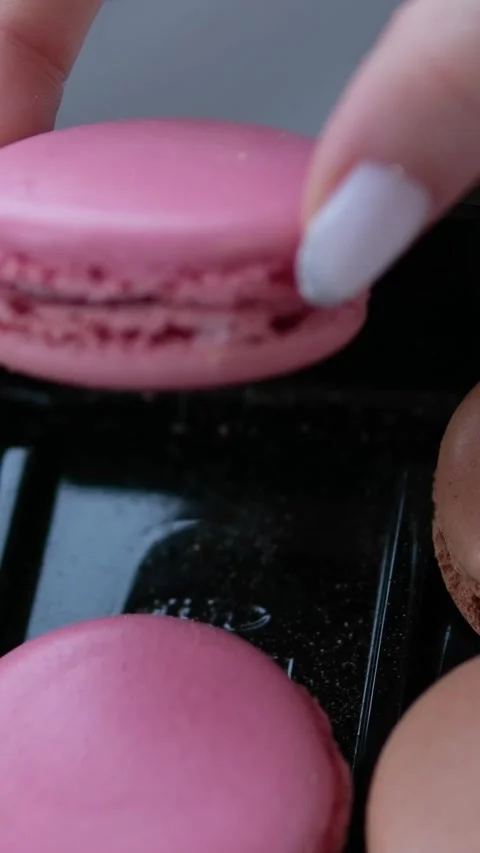 Close-up of assorted colorful macarons arranged in a display case with light Stock Footage 302104076