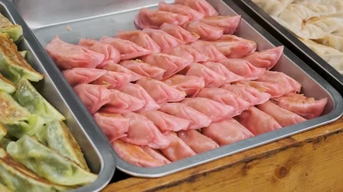 Close-up of assorted green and pink dumplings displayed in trays on street food Stock Footage 284342036