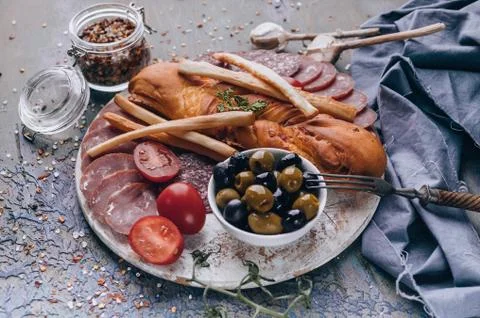 Close-up assorted from meat and cheese on a round chopping board. Raw smoked  Stock Photos